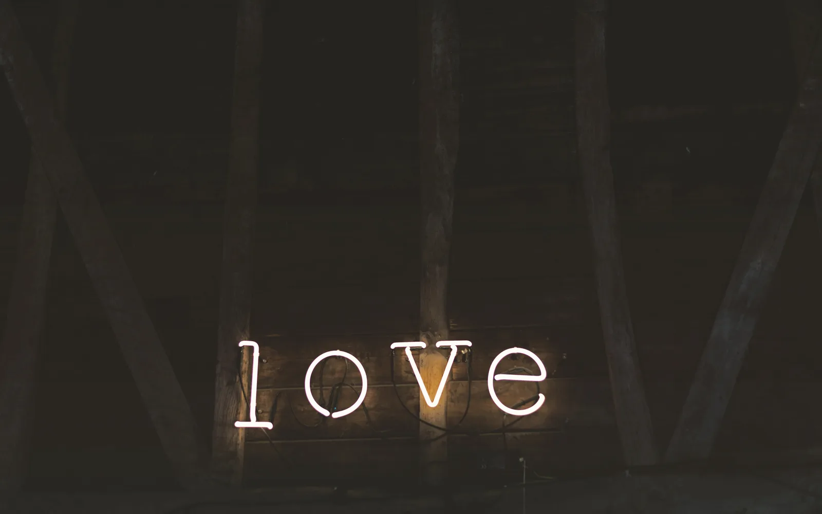 A glowing neon sign spelling the word LOVE against a wooden wall